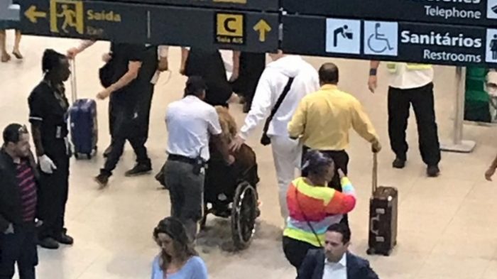 Alcione cai na escada rolante de aeroporto e sai do local em cadeira de rodas